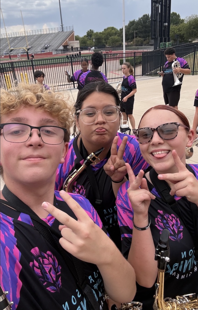 Three friends in matching uniforms making peace signs.