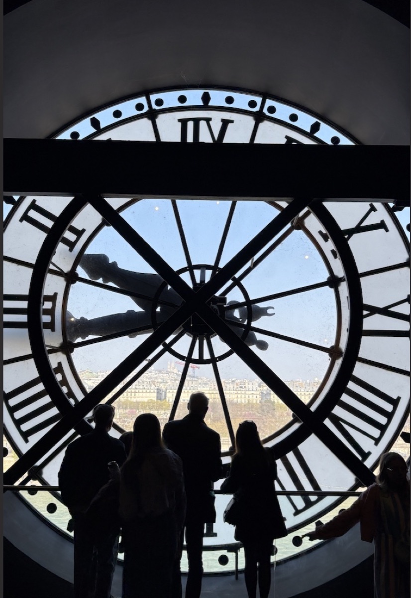People silhouetted in front of a huge clock.